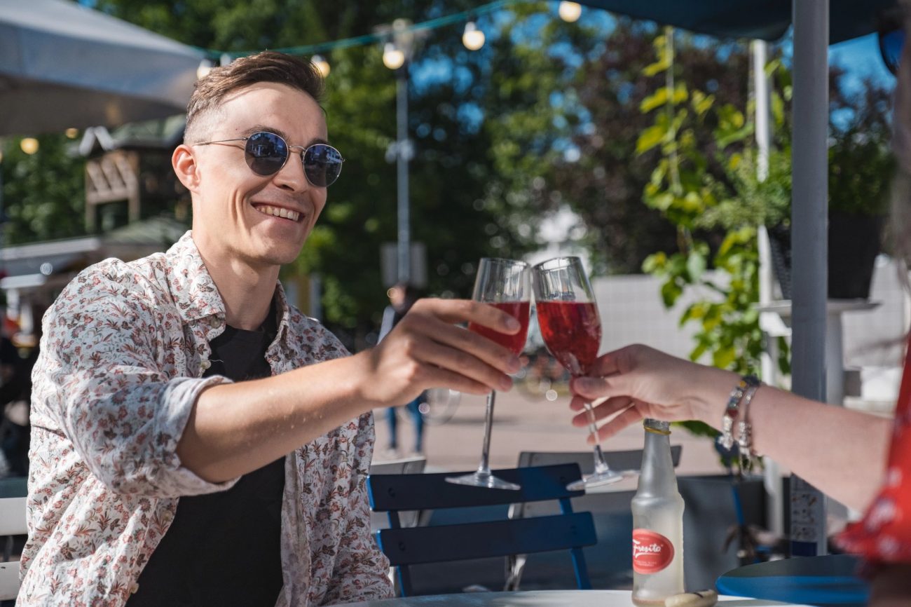 Kaksi henkilö nautiskelee juomaa terassilla kesällä